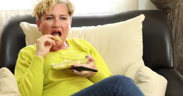 Portrait Relaxed Blonde Woman Sitting Sofa Eating Junk Food Watching — ストック動画