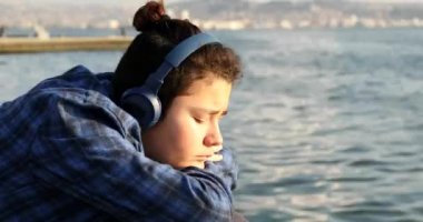 Portrait Of A Young Handsome Sad Teenage Boy With Headphone Looking To Camera At The Seaside