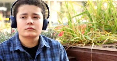 Portrait Of A Young Handsome Caucasian Teenage Boy Listening To Music In The Streets Outdoors