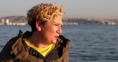 Orta yaşlı, depresyonda olan, deniz kenarında oturan üzgün kadın.