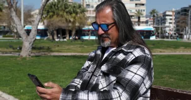 Ευτυχισμένος Μεσήλικας Άντρας Που Χρησιμοποιεί Smartphone Στο City Park — Αρχείο Βίντεο
