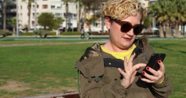 Akıllı telefonlu orta yaşlı sarışın bir kadının portresi.