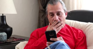 Akıllı telefonlu, orta yaşlı esmer bir adamın portresi.