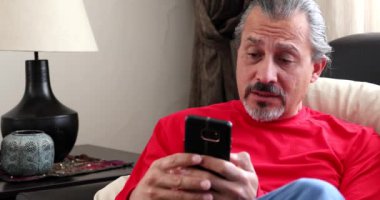 Akıllı telefonlu orta yaşlı esmer bir adamın portresi.