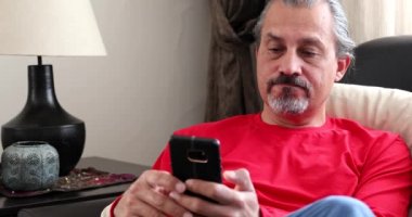 Akıllı telefonlu, orta yaşlı esmer bir adamın portresi.