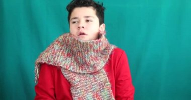 Krom anahtar yeşil ekran arka planına hapşıran, kalın elbiseli genç bir çocuğun kış portresi.