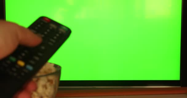 女性手用遥控器在平面绿色荧幕电视上的频道观看小吃电视 — 图库视频影像