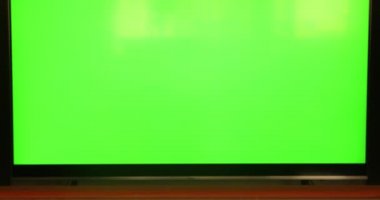 Düz yeşil ekrandaki kanalları uzaktan kumandayla kontrol eden bir kadın. Atıştırmalıklı televizyon izliyor.