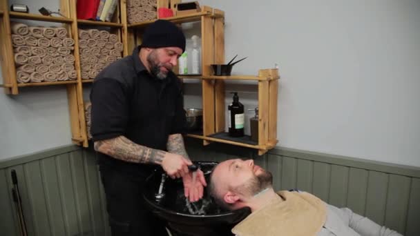 Pánské kadeřnictví a haircutting barber shop nebo vlasy salon. Muž kadeřník dělá střih vousů dospělých mužů v Pánské kadeřnictví. — Stock video