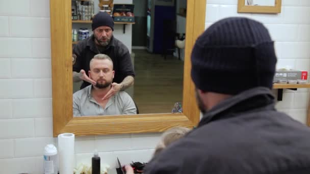 Penteado masculino e corte de cabelo em uma barbearia ou salão de cabeleireiro. Homem cabeleireiro fazendo corte de cabelo barba homens adultos no salão de cabeleireiro masculino . — Vídeo de Stock