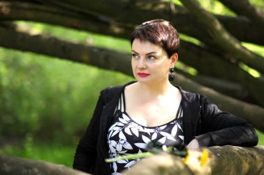 Güzel esmer parkta poz. Siyah elbiseli kaygısız bir yetişkin kadın portresi. 