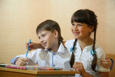 Çocuklar kağıt üzerinde çizin. Yaratıcılık ve eğitim kavramı. Beyaz bir kağıt (tablo üzerine renkli kalemler ile çocuk boyalar)