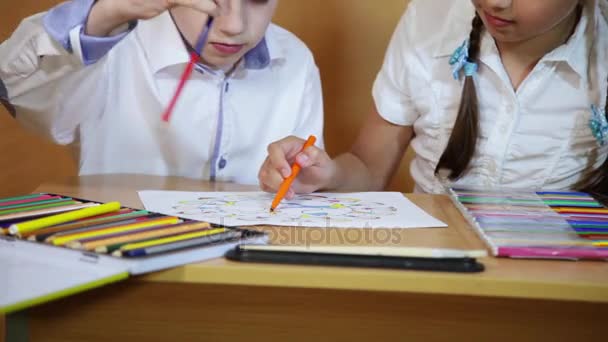 Children draw on paper. Creativity and education concept. The child paints with colored pencils on a white sheet of paper (table) — Stock Video