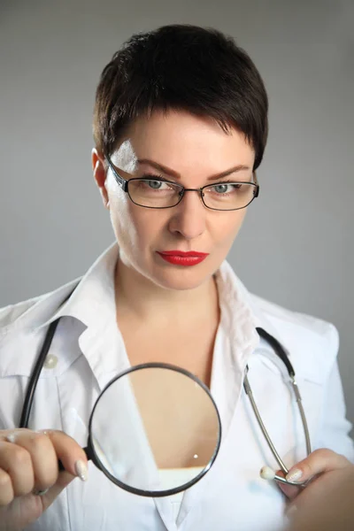 The doctor with a magnifying glass. Beautiful and sexy female doctor in a hospital. — Stock Photo, Image