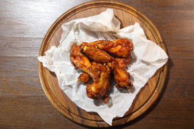 Acı sos, özel bira için hazırlanan tavuk kanatları. Ahşap plaka üzerinde acı sos Tavuk kanatları. Barbekü tavuk kanadı üzerinde ahşap tepsiyi kapatın. Ahşap arka plan kanatlarında pişmiş tavuk.