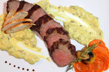 İştah açıcı biftek orta kızartma, kremalı mantar sos parçalar halinde kesin. Biftek ahşap bir masa üzerinde beyaz bir tabak içinde.