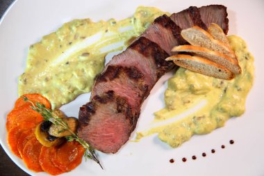 İştah açıcı biftek orta kızartma, kremalı mantar sos parçalar halinde kesin. Biftek ahşap bir masa üzerinde beyaz bir tabak içinde.