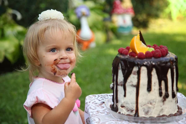 День рождения девушки. Маленькая седовласая двухлетняя девочка пробует торт на день рождения. Девочка празднует второй день рождения . — стоковое фото