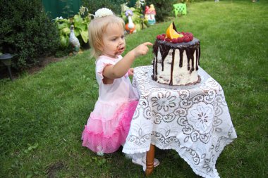 Kız doğum günü. İki yıl küçük bir beyaz saçlı kız bir doğum günü pastası çalışıyor. Küçük kız ikinci doğum günü stok görüntü kutluyor.