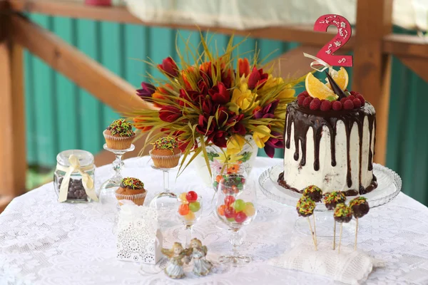 Un tavolo festivo decorato con torta di compleanno con fiori e dolci. Un tavolo con una torta per il compleanno del bambino. Festa di compleanno per bambini . — Foto Stock