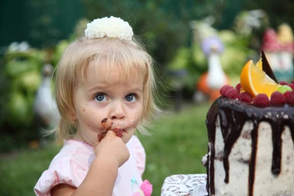 Aniversário de menina. Uma menina de cabelos brancos de dois anos está tentando um bolo de aniversário. Menina comemorando segundo aniversário imagem stock . — Fotografia de Stock