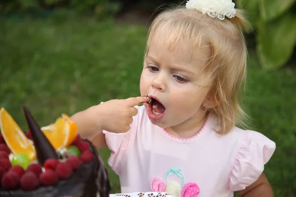 Aniversário de menina. Uma menina de cabelos brancos de dois anos está tentando um bolo de aniversário. Menina comemorando segundo aniversário imagem stock . — Fotografia de Stock