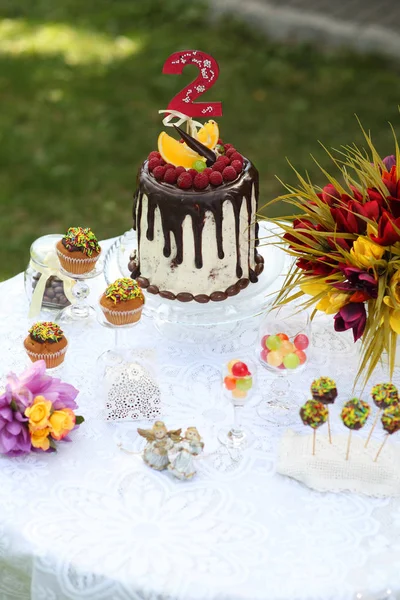 Un tavolo festivo decorato con torta di compleanno con fiori e dolci. Un tavolo con una torta per il compleanno del bambino. Festa di compleanno per bambini . — Foto Stock
