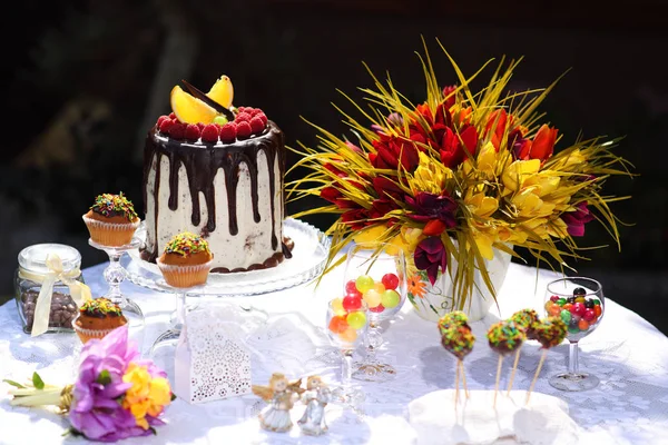 Een feestelijke tafel versierd met cake van de kindverjaardag met bloemen en snoep. Een tabel met een taart voor de verjaardag van het kind. Verjaardagsfeest voor kinderen. — Stockfoto