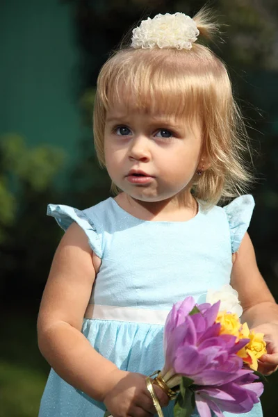 Dulce zâmbitoare fetiță cu păr lung blond, stând pe iarbă în parc de vară, închizând portretul în aer liber. O fetiţă adorabilă pe iarbă. Fetiță în grădină — Fotografie, imagine de stoc