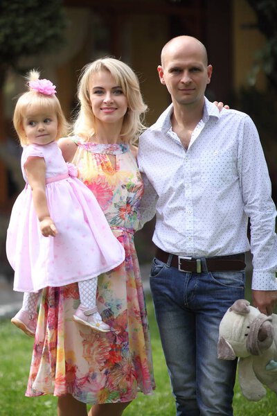 Dad, mom and little beautiful daughter. Happy young family playing on the grass - stock image