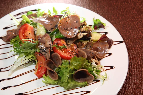 Salata sebze ve otlar, sığır eti dilim giyinmiş beyaz tabakta sos ile. 