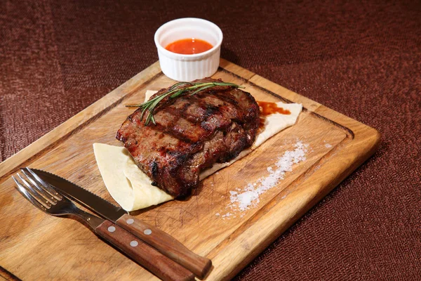 Filete medio asado en una tabla de madera con salsa y sal. — Foto de Stock