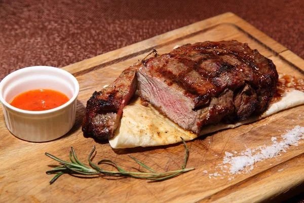 Steak medium roast on a wooden board with sauce and salt. — Stock Photo, Image