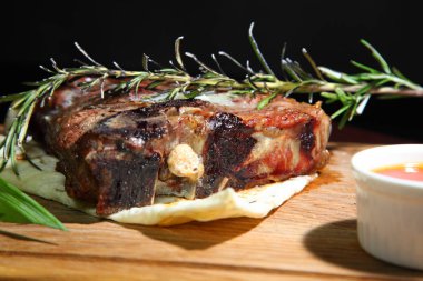 Biftek Tibon orta pişmiş, ahşap bir tahtada sos ve tuz ile..