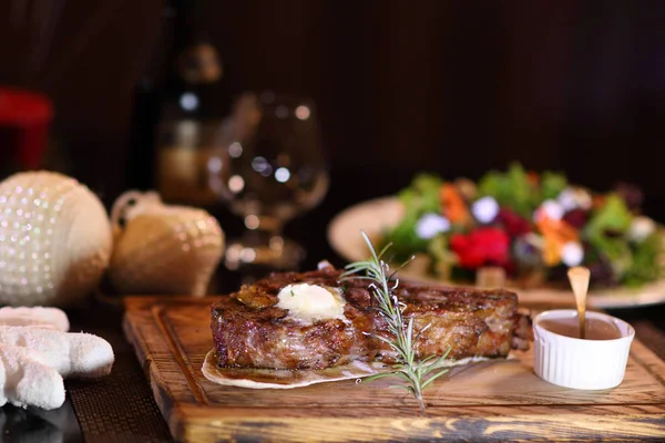 Rib eye steak on the christmas table. Steak rib eye roast on a wooden board with sauce and salt.