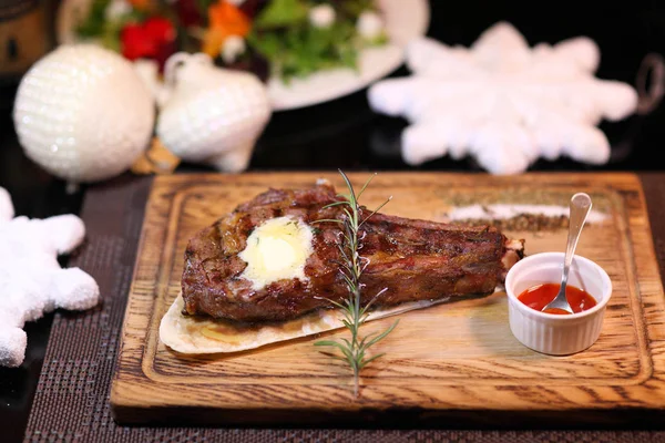 Yılbaşı masasında pirzola. Ahşap bir tahtanın üzerinde biftek ve tuz. Tahta tabakta biftek..