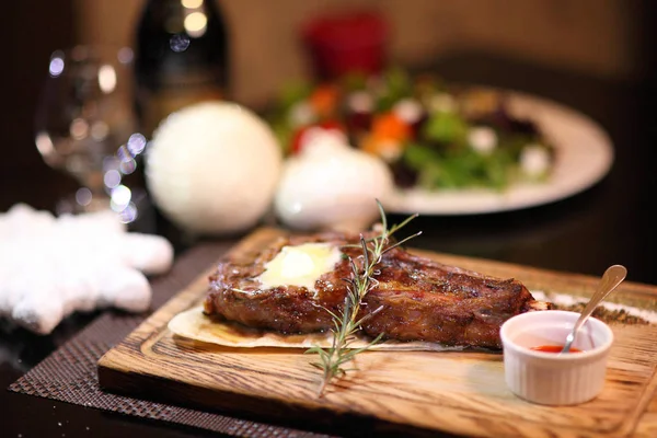 Rib eye steak on the New Year\'s table. Steak rib eye roast on a wooden board with sauce and salt. Beef steak on wooden plate.