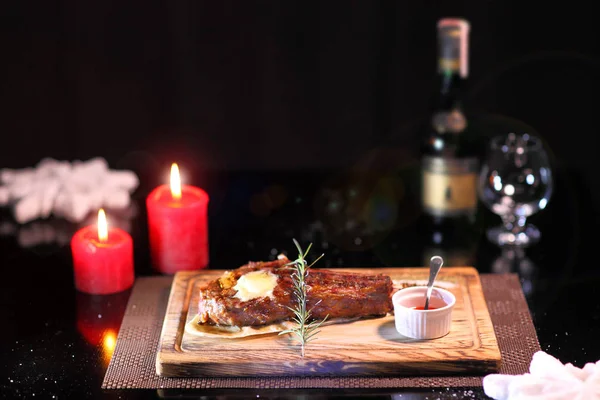 Yılbaşı masasında pirzola. Ahşap bir tahtanın üzerinde biftek ve tuz. Tahta tabakta biftek..