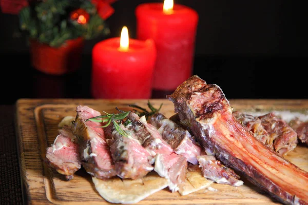 Bordaszelet a karácsonyi asztalnál. Steak borda sült egy fa tábla mártással és sóval. — Stock Fotó