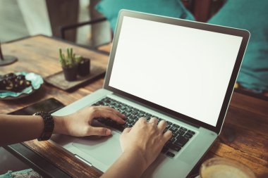 Kahve dükkanında dizüstü bilgisayar kullanan genç bir kadın.