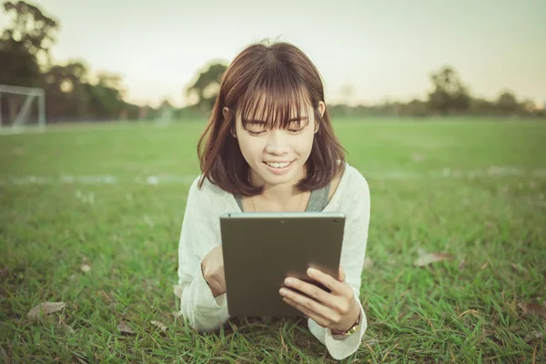 Vacker flicka med hjälp av Tablet PC i grön park. — Stockfoto