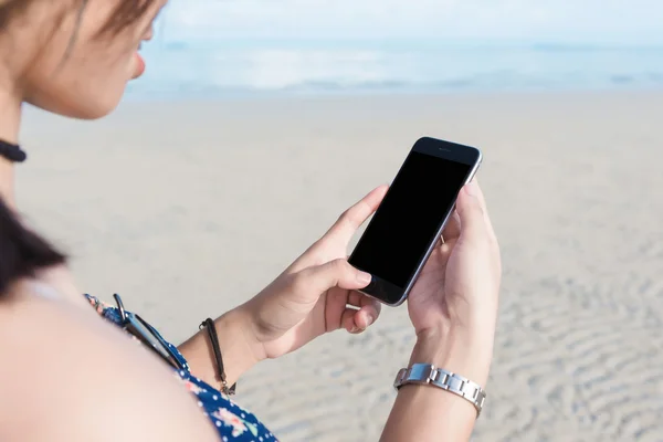 Piękna kobieta ręcznie za pomocą inteligentnego telefonu na plaży. — Zdjęcie stockowe