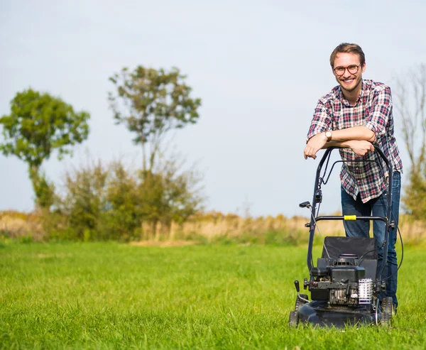 Jeune homme tondre l'herbe — Photo