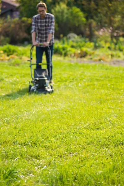 Jeune homme tondre l'herbe — Photo