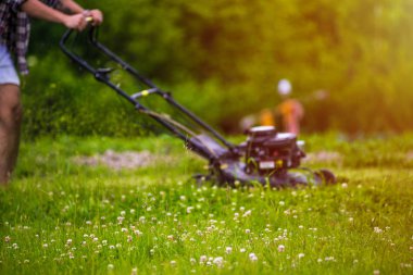 Genç adam çim biçiyor.