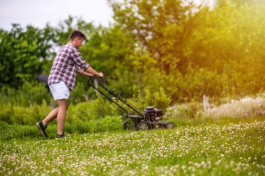 Genç adam çim biçiyor.