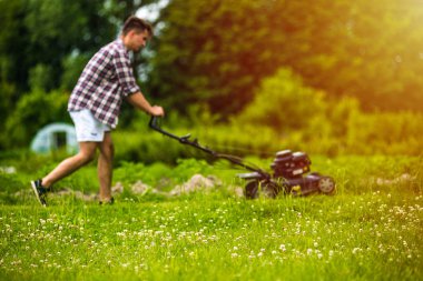Genç adam çim biçiyor.