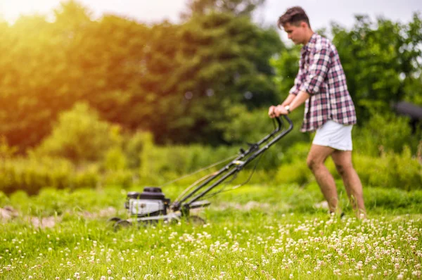 Genç adam çim biçiyor.