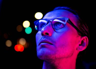 Modern kırmızı ve mavi ışıklı gözlüklü genç bir adamın portresi.