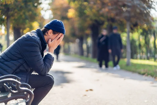 Besorgter junger Mann an einem Herbsttag auf einer Bank — Stockfoto